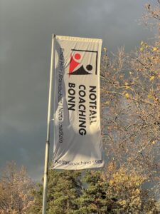 Die Fahne der Firma Notfall Coaching Bonn wird von Sonnenstrahlen angeleuchtet.