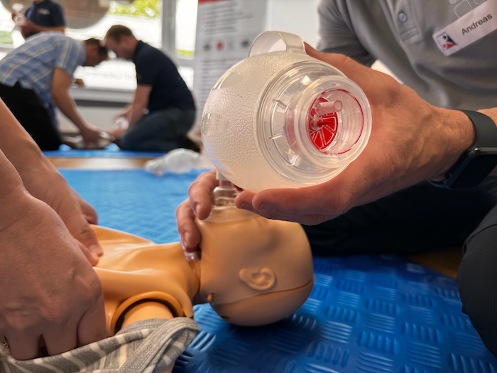 2 Teilnehmer trainieren die Reanimation an einem Säugling. Eine Person führt die Herzdruckmassage aus und die andere beatmet das Kind mit einem Beatmungsbeutel.