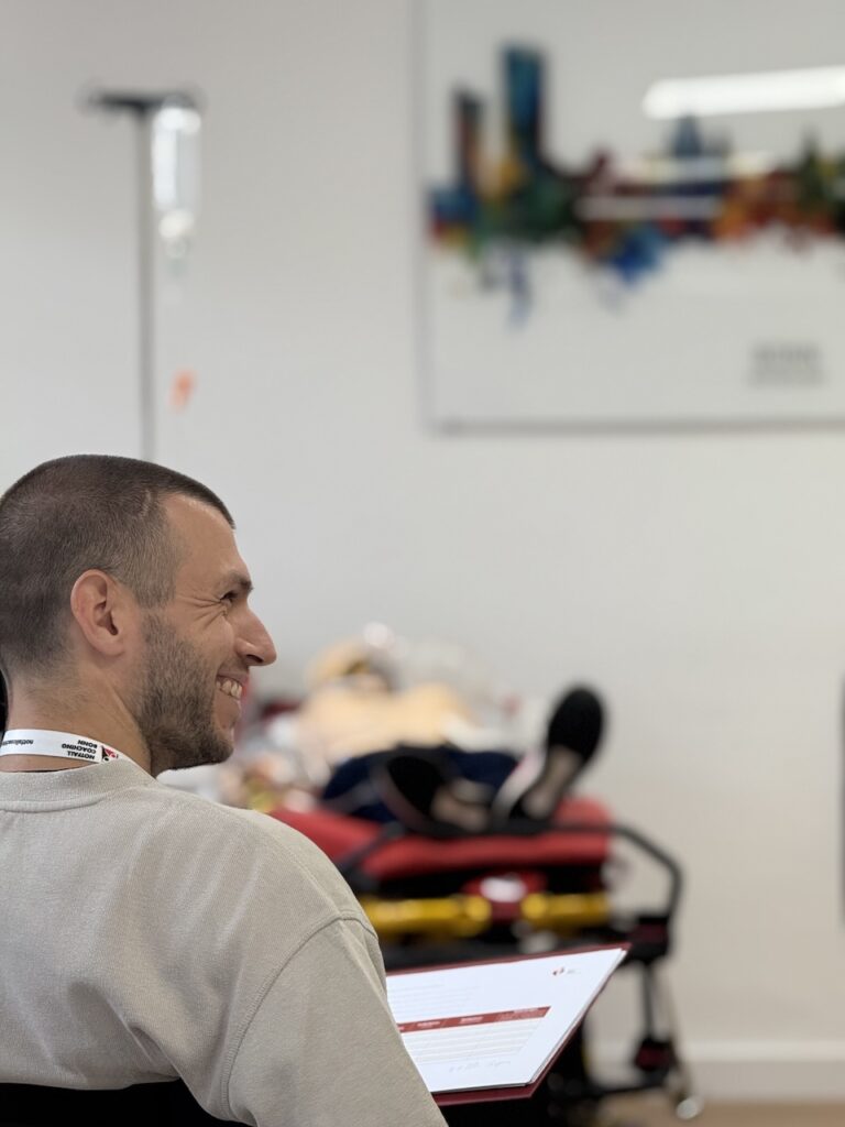 Teilnehmer im Debriefing vom ACLS Kurs lächelt den anderen Personen zu.