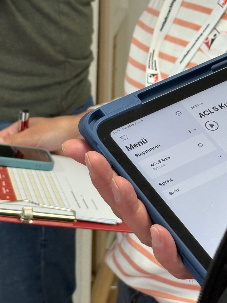 Teilnehmerin hält ein iPad für das Zeitmanagement während einer Simulation im ACLS Kurs in der Hand.