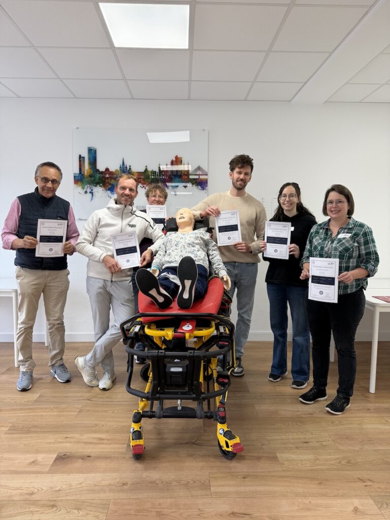 6 glückliche Personen nach bestandenen ACLS Provider Kurs halten ihr Zertifikat hoch.