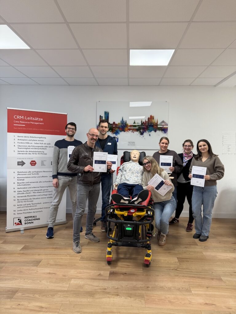 7 glückliche Teilnehmer zeigen ihr ACLS Provider Ausweis. Alle lachen und sind glücklich.